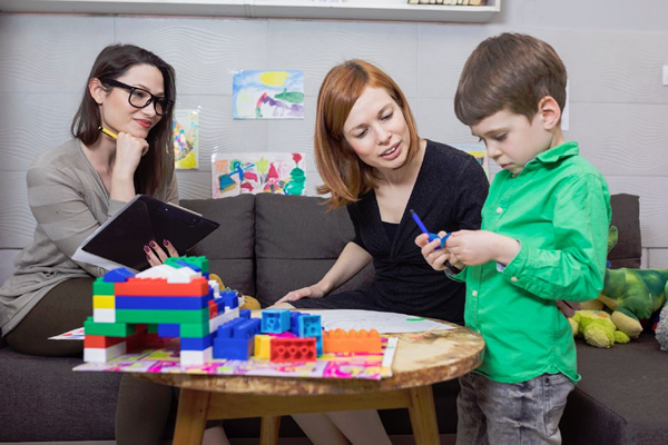 Two female social workers assisting a young male child.