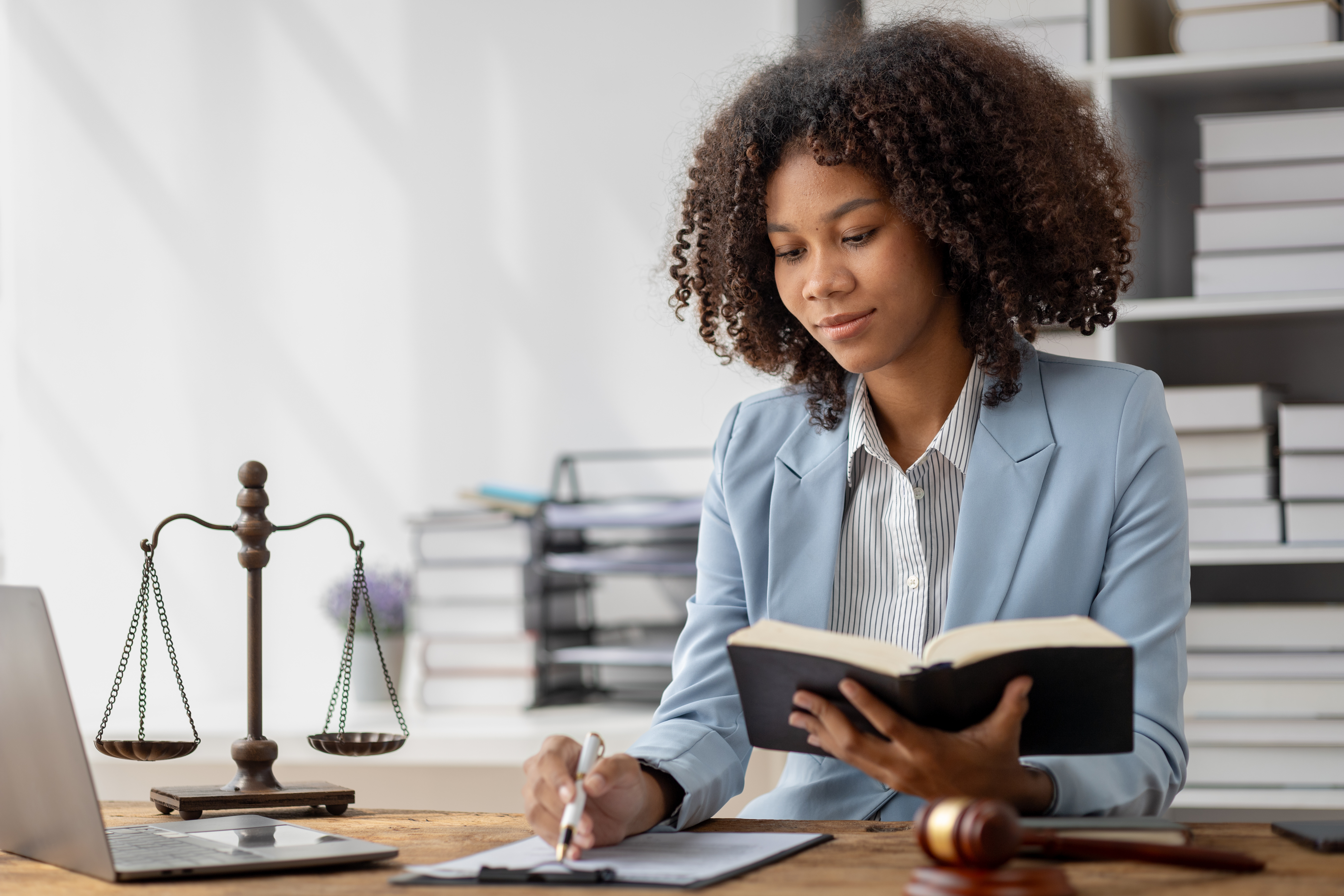 Female lawyer sitting at a desk surrounded by law books.